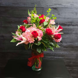 Bouquet of red roses, pink hydrangeas, and lilies in a glass vase