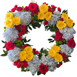 Heart-shaped floral wreath with red and yellow roses and blue hydrangeas