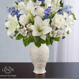 White lilies and roses with blue flowers in a decorative vase