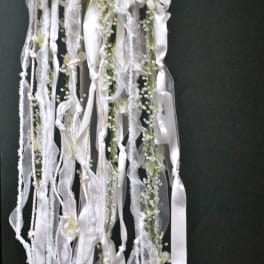 White floral arrangement with long trailing ribbons on a dark background