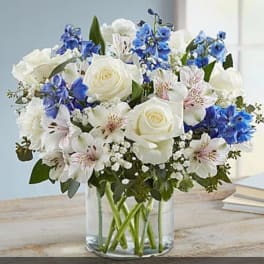 White and blue mixed bouquet in a clear glass vase