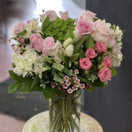 Pink roses and white flowers arranged in a clear glass vase