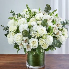 White rose bouquet in a glass vase with green foliage