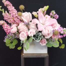 Pink lilies and roses arranged in a white box