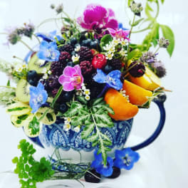 Fruit arrangement in a blue patterned mug with small flowers