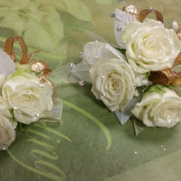 Two small white rose corsages with gold and silver ribbon accents