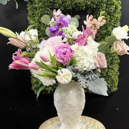 Pink, white, and purple flowers arranged in a white vase