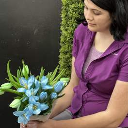 Woman holding a bouquet of blue flowers and green tulips