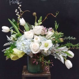 White tulips, roses, and hydrangeas arranged in a green vase