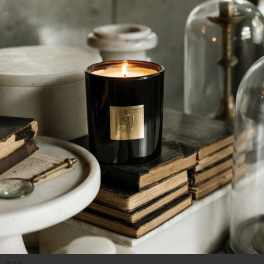 Lit black candle in a glass jar on stacked books
