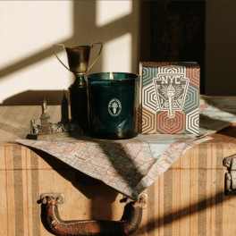 Candle, trophy, and decorative box on a suitcase with a map cloth