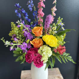 Colorful mixed bouquet in a white vase with roses and tall blooms