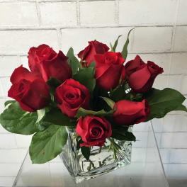 Red roses arranged in a clear square glass vase