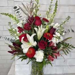 Red and white mixed flower arrangement in a glass vase