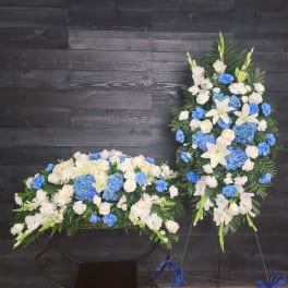 White and blue floral funeral sprays with lilies and roses on stands