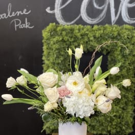 White floral arrangement in a white vase with pink accents