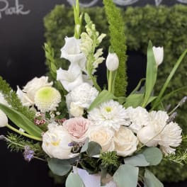 White floral arrangement in a textured vase with tulips and roses