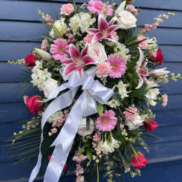 Large pink and white floral spray with a white ribbon bow
