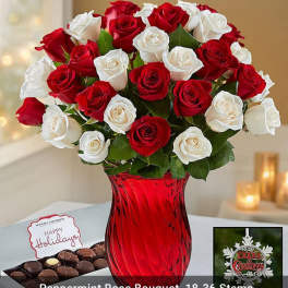 Red and white roses in a red glass vase with chocolates and a holiday card
