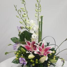 Pink stargazer lilies and purple flowers in a low floral arrangement
