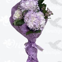 Lavender hydrangea bouquet wrapped in purple paper with a ribbon