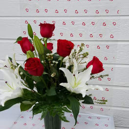 Red roses and white lilies arranged in a clear glass vase