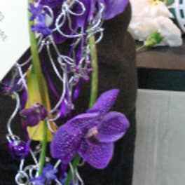 Purple orchid arrangement with silver curling ribbons and yellow calla lilies