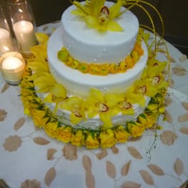 Two-tier white cake decorated with yellow orchids and candles