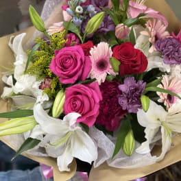 Bouquet of pink and white flowers with roses and lilies wrapped in paper