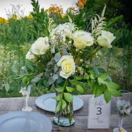 White rose centerpiece in a glass vase on a wedding table