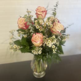 Pink-edged roses in a clear glass vase with small white filler flowers