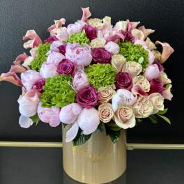 Pink and cream bouquet with roses, peonies, calla lilies, and green hydrangeas in a gold box