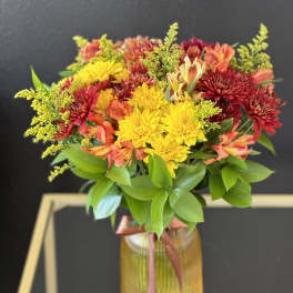 Bouquet of yellow, red, and orange flowers in a ribbed glass vase