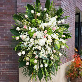 Tall standing spray of white hydrangeas and pale pink and white roses on a wooden easel