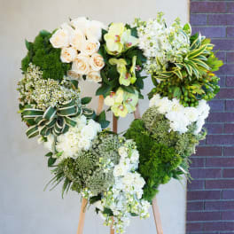 Heart-shaped floral wreath on a wooden easel with white and green flowers