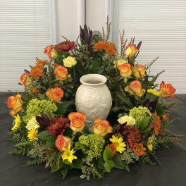 Autumn floral wreath with orange roses and chrysanthemums around a white vase