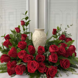 Red roses arranged around a cream ceramic vase