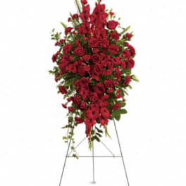 Tall red funeral spray with roses and carnations displayed on a metal easel