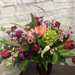 Mixed bouquet in a dark glass vase with pink and red flowers