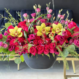 Pink and red roses with yellow orchids in a black bowl vase