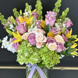 Bouquet of pink roses, green hydrangeas, and yellow lilies in a glass vase