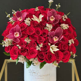 Red rose arrangement with orchids in a white hat box
