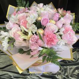 Pink and white bouquet with roses, lilies, and carnations wrapped in gold-trimmed paper