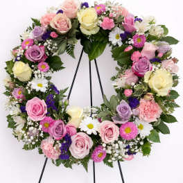 Pastel wreath of roses, daisies, carnations and filler flowers on a black easel stand