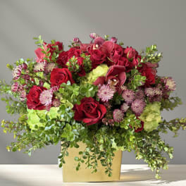 Red roses and pink flowers arranged in a gold box vase