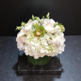 White floral arrangement in a glass vase with green accents