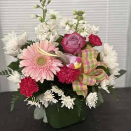 Pink gerbera and rose bouquet in a green vase with a plaid ribbon