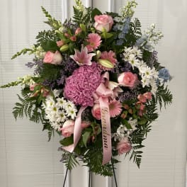Standing floral spray with pink roses, lilies, and hydrangea on an easel