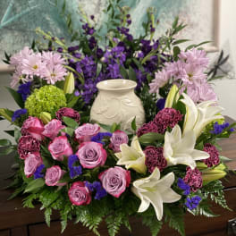 Pink roses and white lilies arranged around a ceramic urn