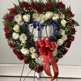 Heart-shaped floral wreath with red and white roses on a stand